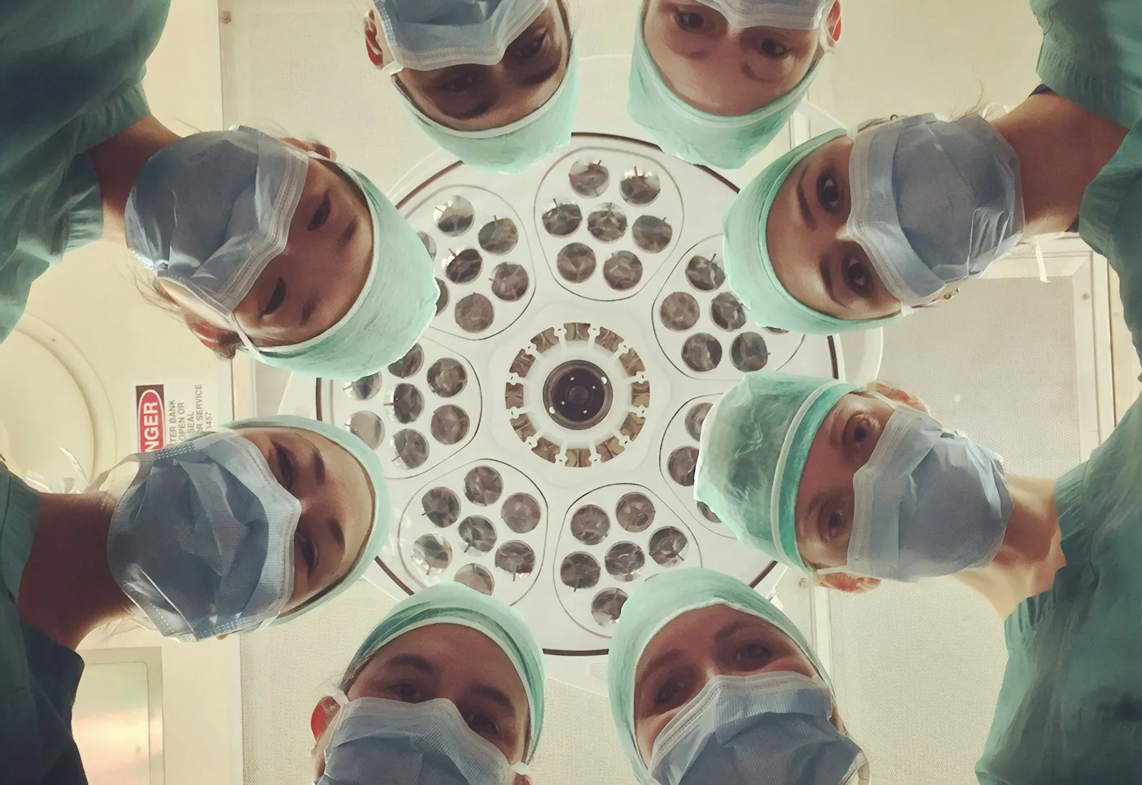 Surgical team looking down into camera around an operating light